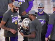 Los Angeles Lakers&#039; Anthony Davis, left, looks at their trophy after beating the Denver Nuggets in an NBA conference final playoff basketball game Saturday, Sept. 26, 2020, in Lake Buena Vista, Fla. The Lakers won 117-107 to win the series 4-1. (AP Photo/Mark J.