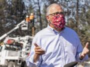 Washington Governor Jay Inslee speaks during a press conference on Thursday, Sept. 10, 2020, in Malden, Wash., while linemen repair a damaged power pole behind him. Inslee was visiting Malden to meet with first responders and community members after the town was damaged by a wildfire on Monday.