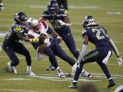 New England Patriots quarterback Cam Newton is tackled by Seattle Seahawks safety Ugo Amadi, left, as linebacker Jordyn Brooks, second from right, and cornerback Tre Flowers, right, provide added pressure.