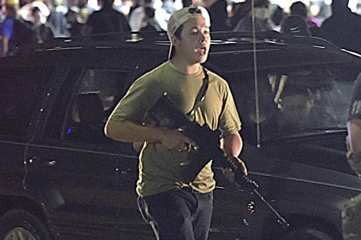 FILE - In this Tuesday, Aug. 25, 2020 file photo, Kyle Rittenhouse carries a weapon as he walks along Sheridan Road in Kenosha, Wis., during a night of unrest following the weekend police shooting of Jacob Blake. Rittenhouse, a 17-year-old accused of killing two protesters days after Jacob Blake was shot by police in Kenosha, Wisconsin, faces a hearing Friday, Sept. 25, 2020 on whether he should be sent to Wisconsin to stand trial on homicide charges that could put him in prison for life.