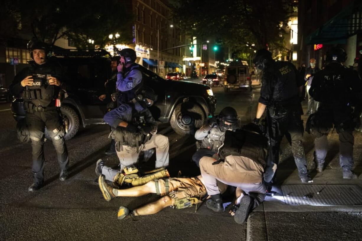 FILE - In this Aug. 29, 2020, file photo, a man who later died is treated after being shot at a demonstration in Portland, Ore. Once hailed as one of the most livable cities in the U.S., Portland, Oregon, is grappling with an uncertain future as it reaches a stunning benchmark: 100 consecutive nights of racial injustice protests marred by vandalism, chaos -- and now, the killing of a supporter of President Donald Trump.