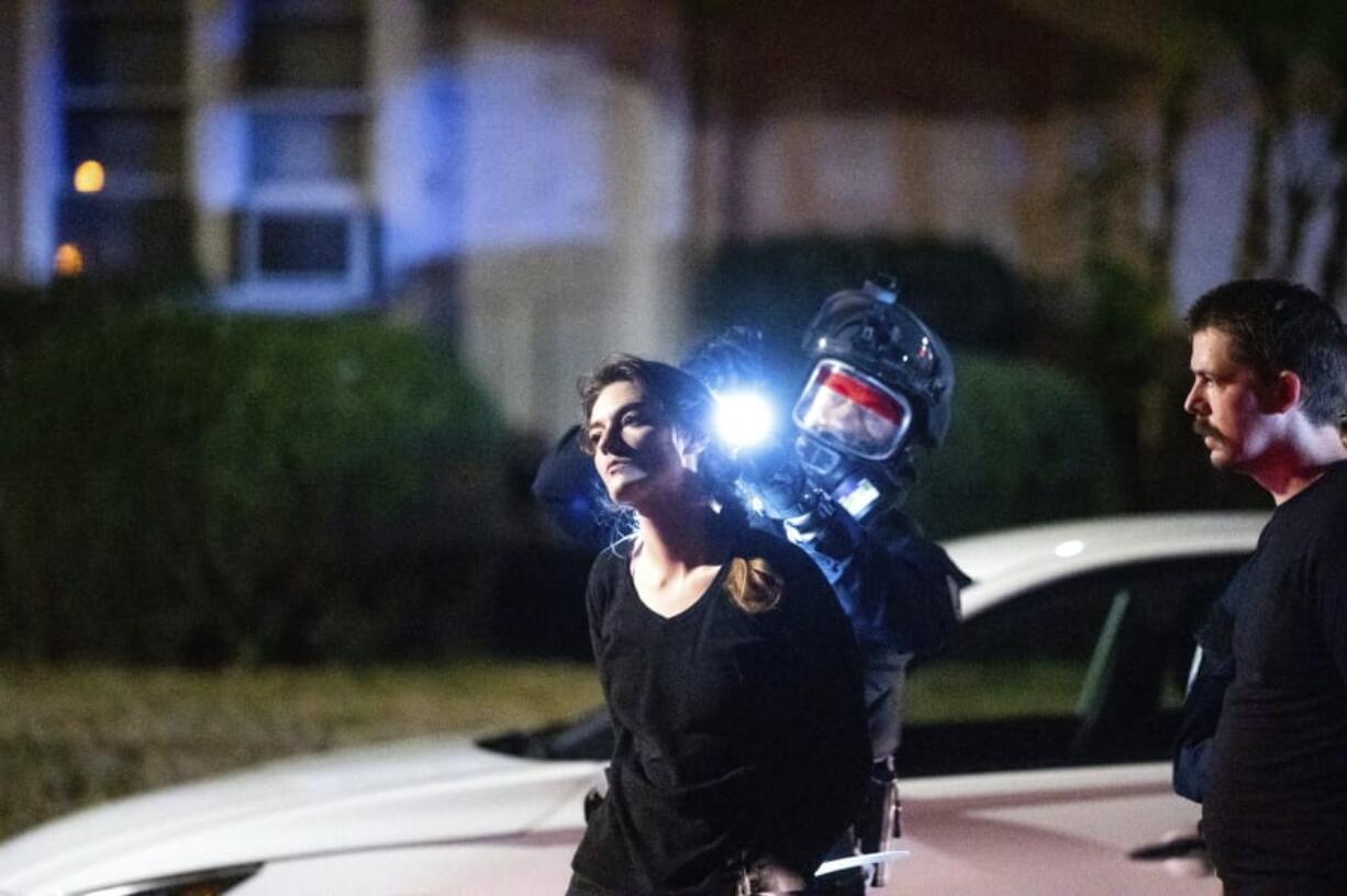 A police officer searches a woman during the 100th consecutive day of demonstrations in Portland, Ore., on Saturday, Sept. 5, 2020. The demonstrations, which began over the killing of George Floyd, have led to two deaths and frequent clashes between protesters and law enforcement.