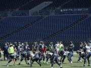 Seattle Seahawks quarterback Russell Wilson, center, waits for the snap during warmups in front of empty seats at CenturyLink Field before an NFL football mock game, Wednesday, Aug. 26, 2020, in Seattle. (AP Photo/Ted S.