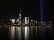 FILE - In this Sept. 11, 2017, file photo, the Tribute in Light illuminates in the sky above the Lower Manhattan area of New York, as seen from across the Hudson River in Jersey City, N.J. The coronavirus pandemic has reshaped how the U.S. is observing the anniversary of 9/11. The terror attacks&#039; 19th anniversary will be marked Friday, Sept. 11, 2020, by dueling ceremonies at the Sept. 11 memorial plaza and a corner nearby in New York.