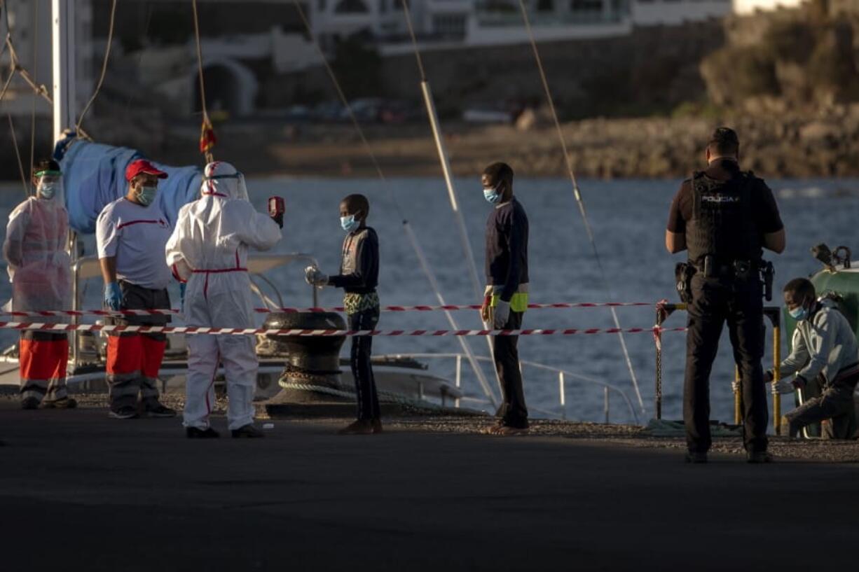 A boy has his temperature taken as he arrives with others migrants at the Arguineguin port in Gran Canaria island, Spain, after being rescued in the Atlantic Ocean by emergency workers on Thursday, Aug. 20, 2020. Migrants and asylum seekers are increasingly crossing a treacherous part of the Atlantic Ocean to reach the Canary Islands, a Spanish archipelago near West Africa, in what has become one of the most dangerous migration routes to European territory.