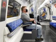 A man wears a face mask to protect against infection from coronavirus as he sits on an Underground train, in London, Tuesday, Sept. 8, 2020.