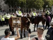 A protester holds up a placard in front of police officers during a &quot;Resist and Act for Freedom&quot; protest against a mandatory coronavirus vaccine, wearing masks, social distancing and a second lockdown, in Trafalgar Square, London, Saturday, Sept. 19, 2020.