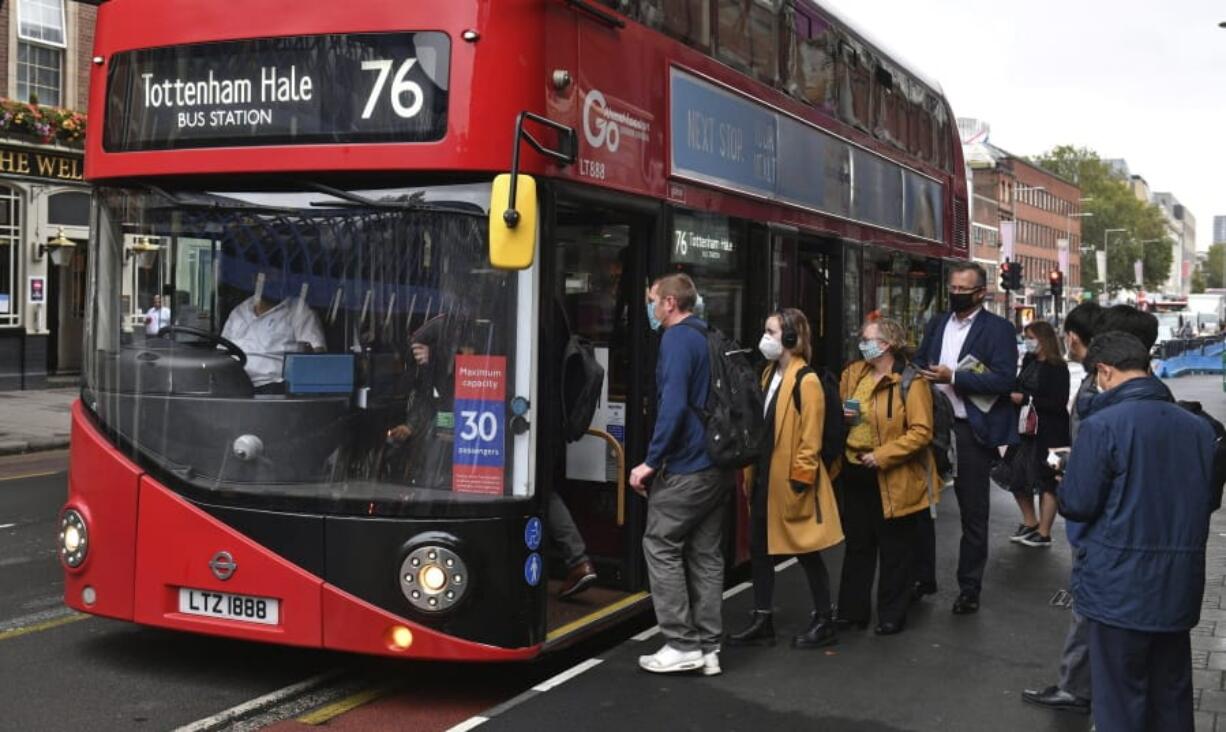 People board a bus outside Waterloo station in London, Wednesday, Sept. 23, 2020, after Prime Minister Boris Johnson announced a range of new restrictions to combat the rise in coronavirus cases in England, Wednesday, Sept. 23, 2020.