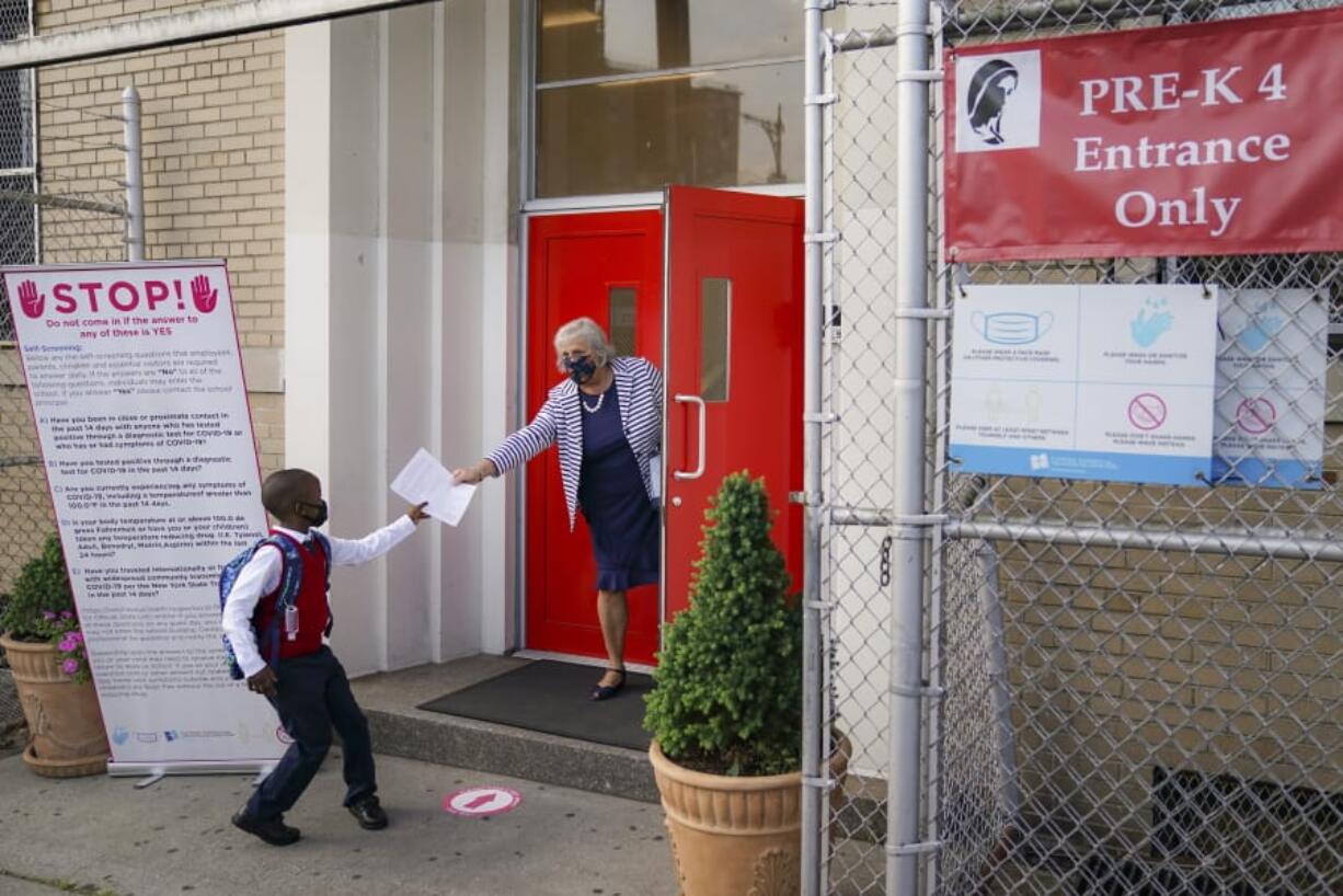 FILE - In this Sept. 9, 2020, file photo, a student wears a protective masks as they arrive for classes at the Immaculate Conception School while observing COVID-19 prevention protocols in The Bronx borough of New York. New York City has again delayed the planned start of in-person learning for most of the more than 1 million students in its public school system. Mayor Bill de Blasio announced Thursday, Sept. 17,  that most elementary school students would do remote-only learning until Sept. 29. Middle and high schools would stay remote through Oct.