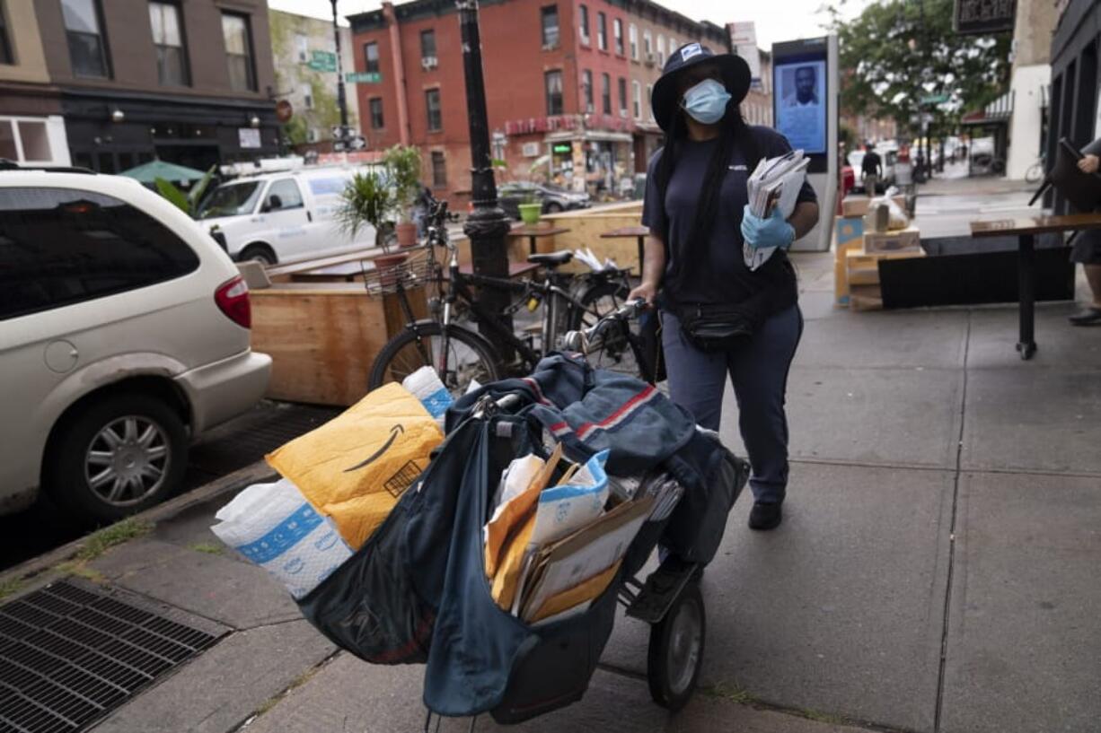 A postal worker delivers the mail, Tuesday, Sept. 1, 2020 in Brooklyn, N.Y..