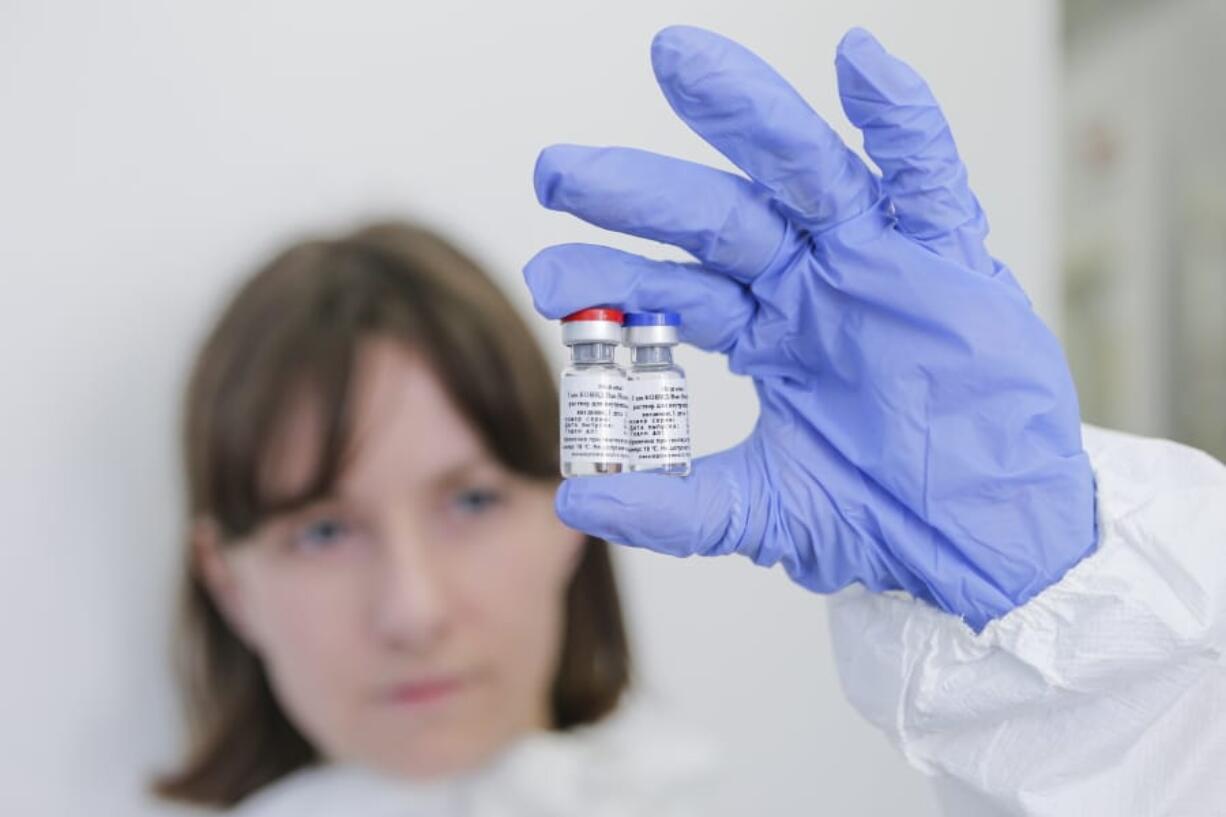 In this handout photo taken on Thursday, Aug. 6, 2020, and provided by Russian Direct Investment Fund, an employee shows a new vaccine at the Nikolai Gamaleya National Center of Epidemiology and Microbiology in Moscow, Russia.