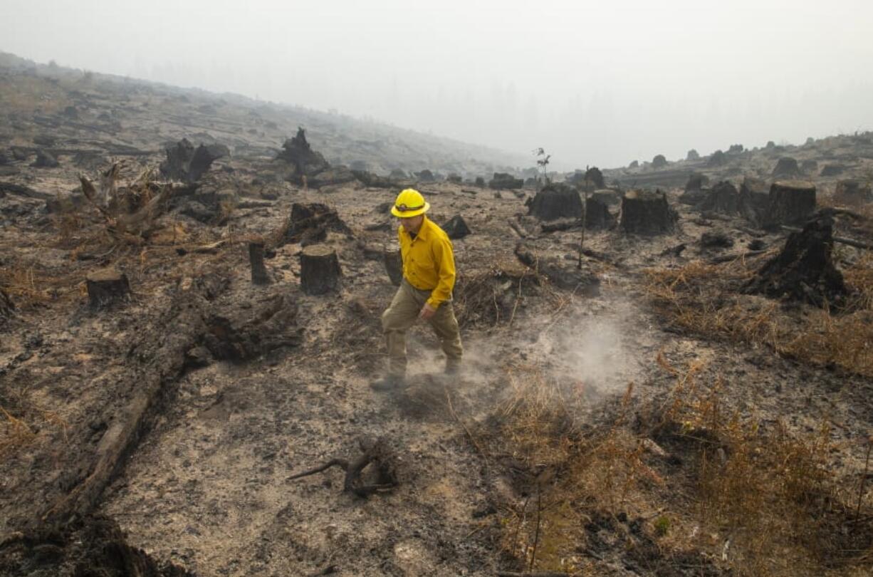 Marcus Kauffman with the Oregon Department of Forestry, walks through a burned out area of the Holiday Farm Fire along the southwest edge of the burn area above Deerhorn, Ore., Thursday, Sept. 17, 2020.