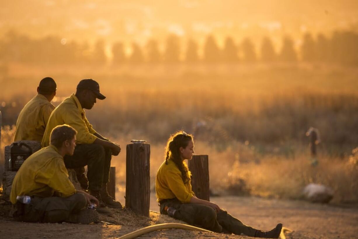 Firefighters rest during a wildfire in Yucaipa, Calif., Saturday, Sept. 5, 2020. Firefighters trying to contain the massive wildfires in Oregon, California and Washington state are constantly on the verge of exhaustion as they try to save suburban houses, including some in their own neighborhoods. (AP Photo/Ringo H.W.