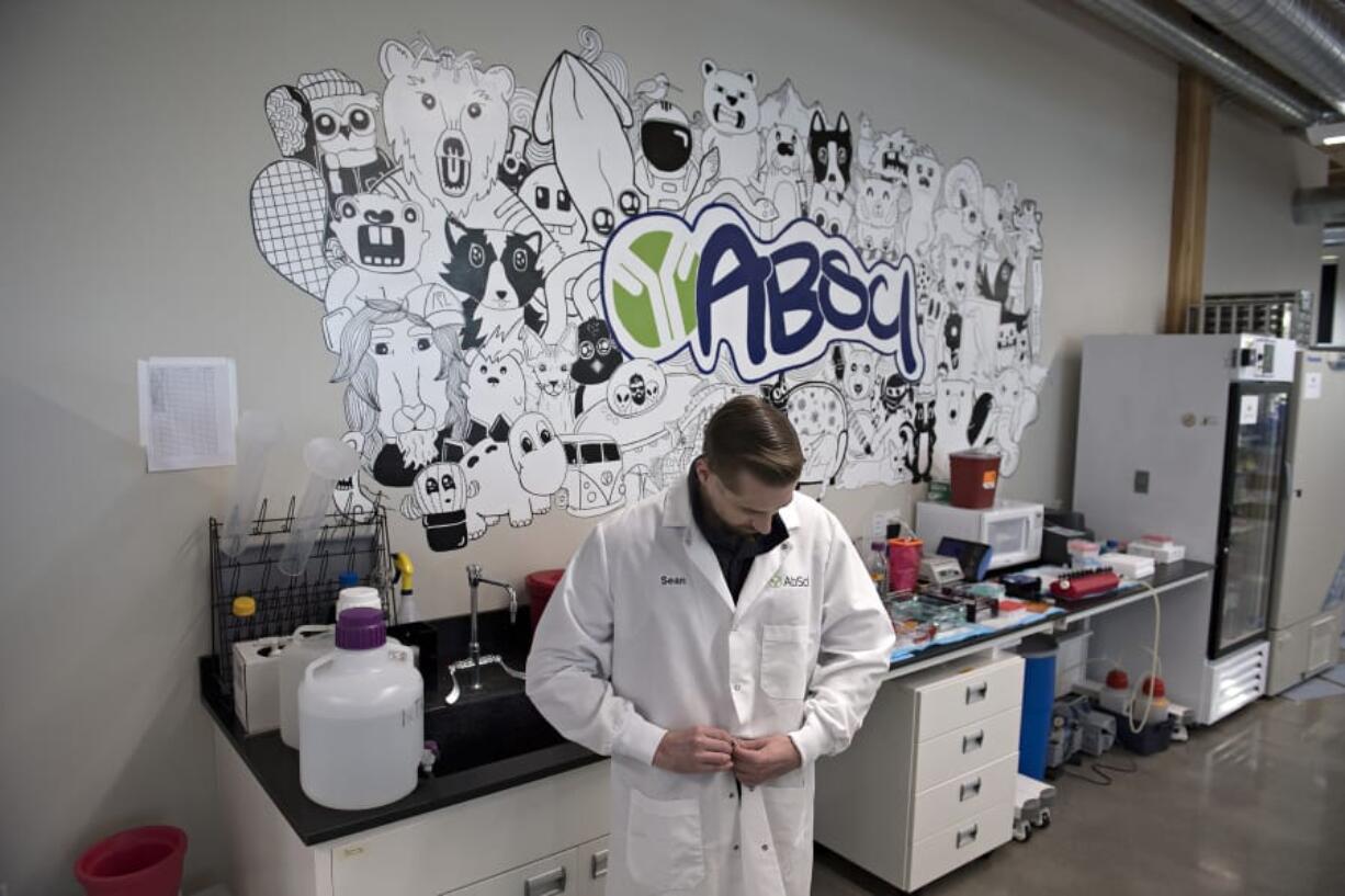 Sean McClain, founder and CEO of AbSci in downtown Vancouver, prepares his lab coat before pausing for a portrait in his company&#039;s lab. The company is preparing to start construction on a 60,000-square-foot building in Vancouver to house all operations and employees, according to McClain.