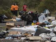 Workers cleaned up a large amount of garbage near a homeless camp along Burnt Bridge Creek in east Vancouver on Thursday. Fewer routine cleanups have been happening around the city due to COVID-19.