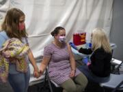 Abby Atalla, 10, comforts her mom Lara as she gets a flu shot from medical assistant Jillian Kinsella at Kaiser Permanente's Cascade Park office in Vancouver on Saturday. The office's flu shot clinic is set up in an outdoor tent in order to maintain safe social distancing due to the COVID-19 pandemic.