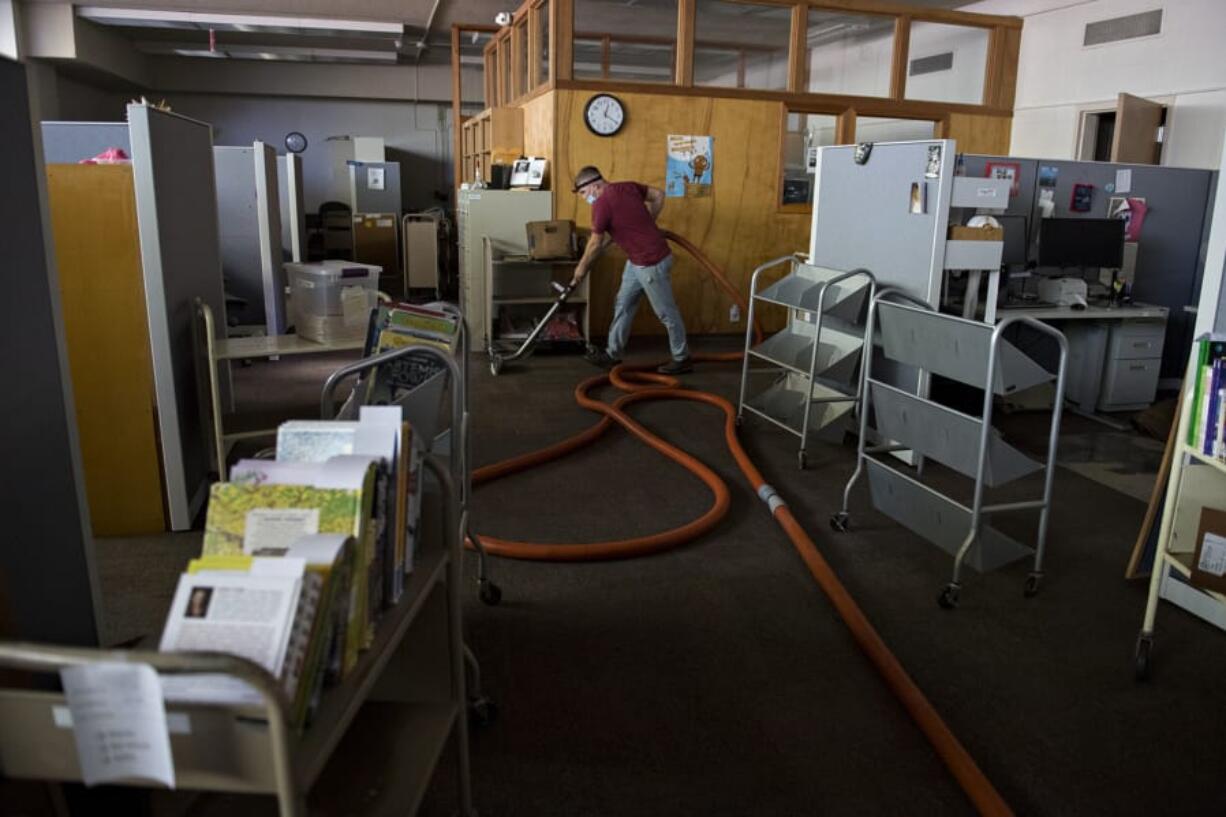 Trevor Burns of D&amp;H Carpet Cleaning helps remove remaining water in the basement carpet and subfloor at Fort Vancouver Regional Library Operations Center on Monday afternoon. A ruptured water main flooded part of the facility over the weekend.