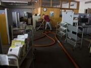 Trevor Burns of D&amp;H Carpet Cleaning helps remove remaining water in the basement carpet and subfloor at Fort Vancouver Regional Library Operations Center on Monday afternoon. A ruptured water main flooded part of the facility over the weekend.