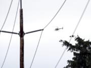 Clark Public Utilities staff ride in a helicopter to inspect vegetation around a transmission line in northwestern Camas. The utility provider is hoping that adding helicopter and drone flights will allow it to be more proactive in monitoring vegetation and making sure its power lines stay clear.