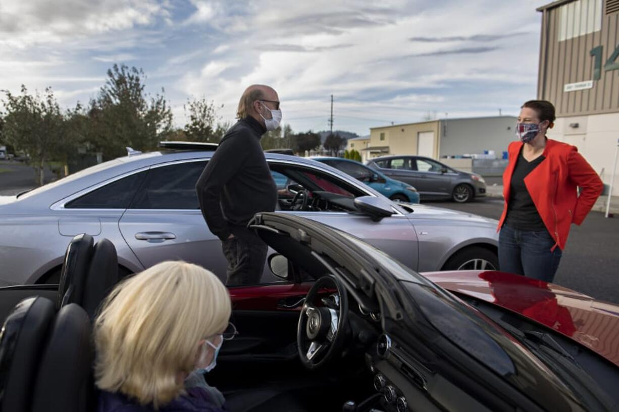 Jo Ellen Jarvis and Dave Watson wear masks while getting a few minutes to chat with congressional candidate Carolyn Long before a drive-in town hall in Washougal on Monday.