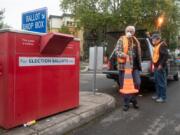 Elections workers John Waterbury, left, and Les Stark set up a safety cone before collecting ballots from an official drop box near the Clark County Elections Office on Saturday morning, October 17, 2020.