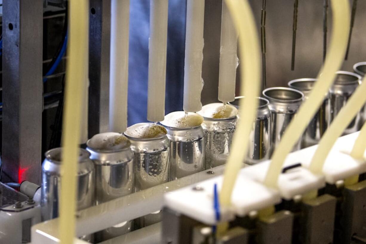 Suds from 54?40&#039; Brewing&#039;s 1862 Mexican Lager overflow aluminum cans during a production run at the brewery in Washougal. Portland-based Craft Canning supplies contract canning services for 54?40&#039; and several other Clark County breweries.