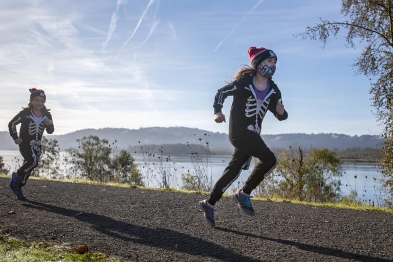 Eight-year-old Sophia Campbell, left, runs behind Emily Corsen, 10, in WhyRacing’s Scary Run on Saturday morning, October 31, 2020, in Washougal.