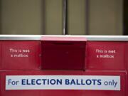 Voters swing by a downtown Vancouver ballot drop box while participating in early voting Thursday afternoon.