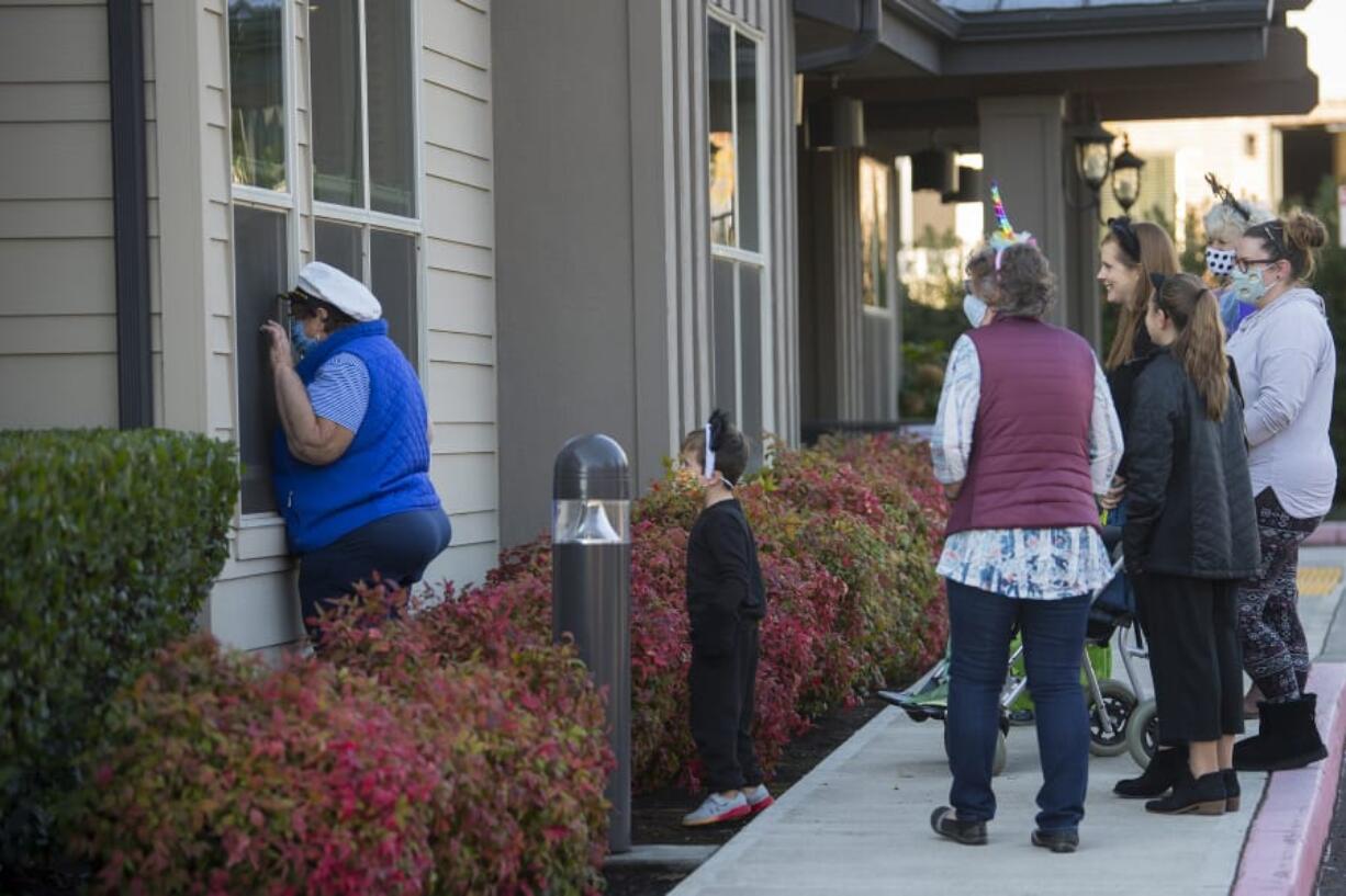 Wendy Mikota, left, of Felida pauses to brighten the day of her husband, Roger, and other residents while joining a small group of local Halloween enthusiasts Thursday during a parade around the exterior of Bonaventure of Salmon Creek. The group played recorders and kazoos, did the &quot;Hokey Pokey&quot; and sang songs to celebrate the season with residents who have been isolated because of COVID-19 concerns.