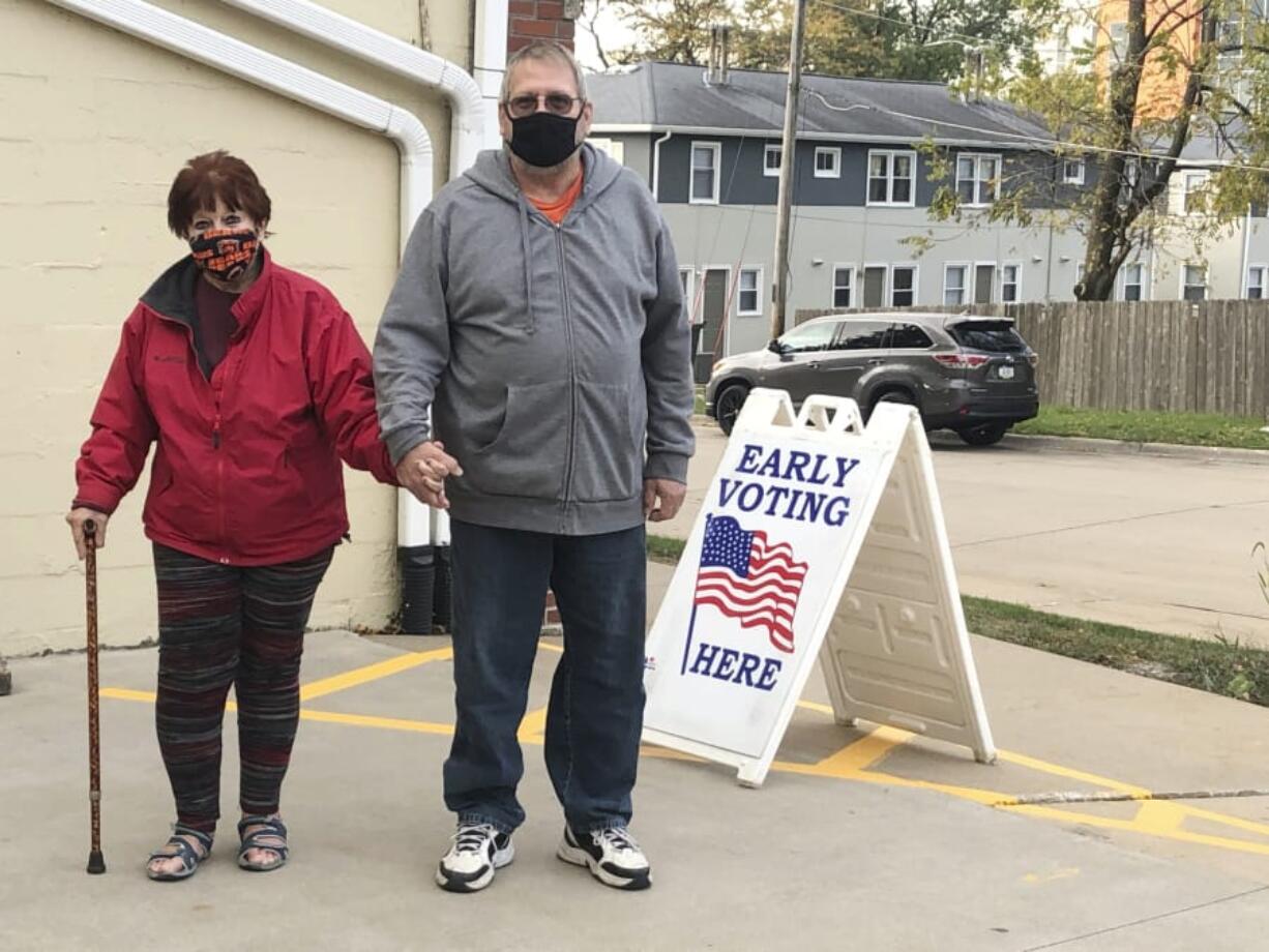 Tim and Pat Tompkins pause for a picture on their way to early vote in Bettendorf, Iowa, Friday, Oct. 16, 2020. Tompkins said he and his wife, Pat, were concerned about coronavirus exposure in bigger crowds and brought their own sanitizer, but were determined to vote.