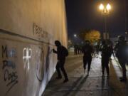 Protesters tag a wall with spray paint in downtown Vancouver on Friday night. Some windows also were smashed.