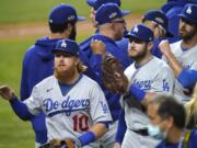 Los Angeles Dodgers' Justin Turner (10) and his teammates celebrate after defeating the San Diego Padres 12-3 in Game 3 of a baseball National League Division Series. Thursday, Oct. 8, 2020, in Arlington, Texas.