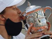 Poland's Iga Swiatek kisses the trophy after winning the final match of the French Open tennis tournament against Sofia Kenin of the U.S. in two sets 6-4, 6-1, at the Roland Garros stadium in Paris, France, Saturday, Oct. 10, 2020.