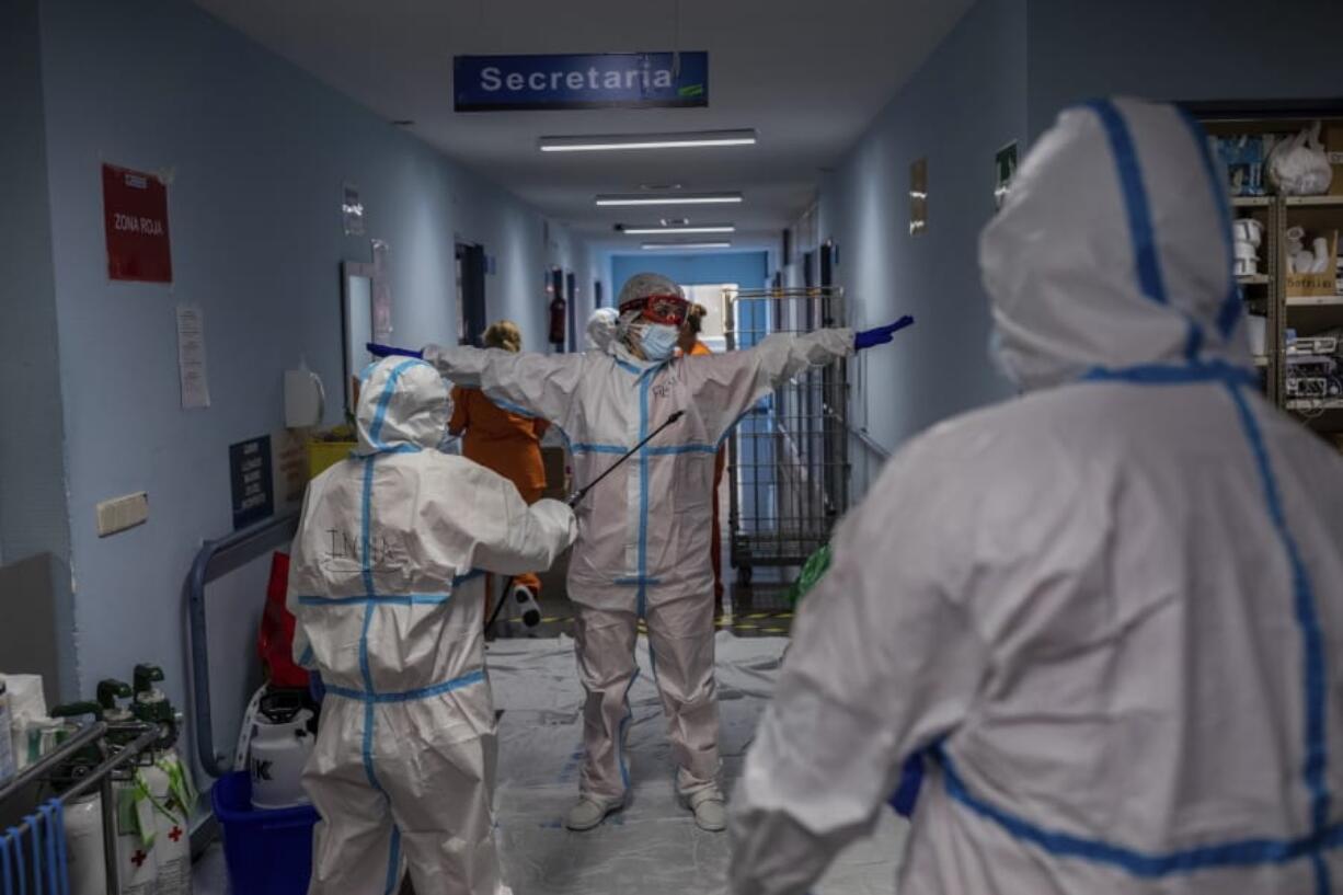 A medical team member is disinfected before leaving the COVID-19 ward at the Severo Ochoa hospital in Leganes, outskirts of Madrid, Spain, Friday, Oct. 9, 2020. At the peak of the first wave, ICU wards were given over to haste, desperation and even cluelessness about what to do. Now, a well-oiled machinery saves some lives and loses others to coronavirus, but without the doomsday atmosphere of March and April.