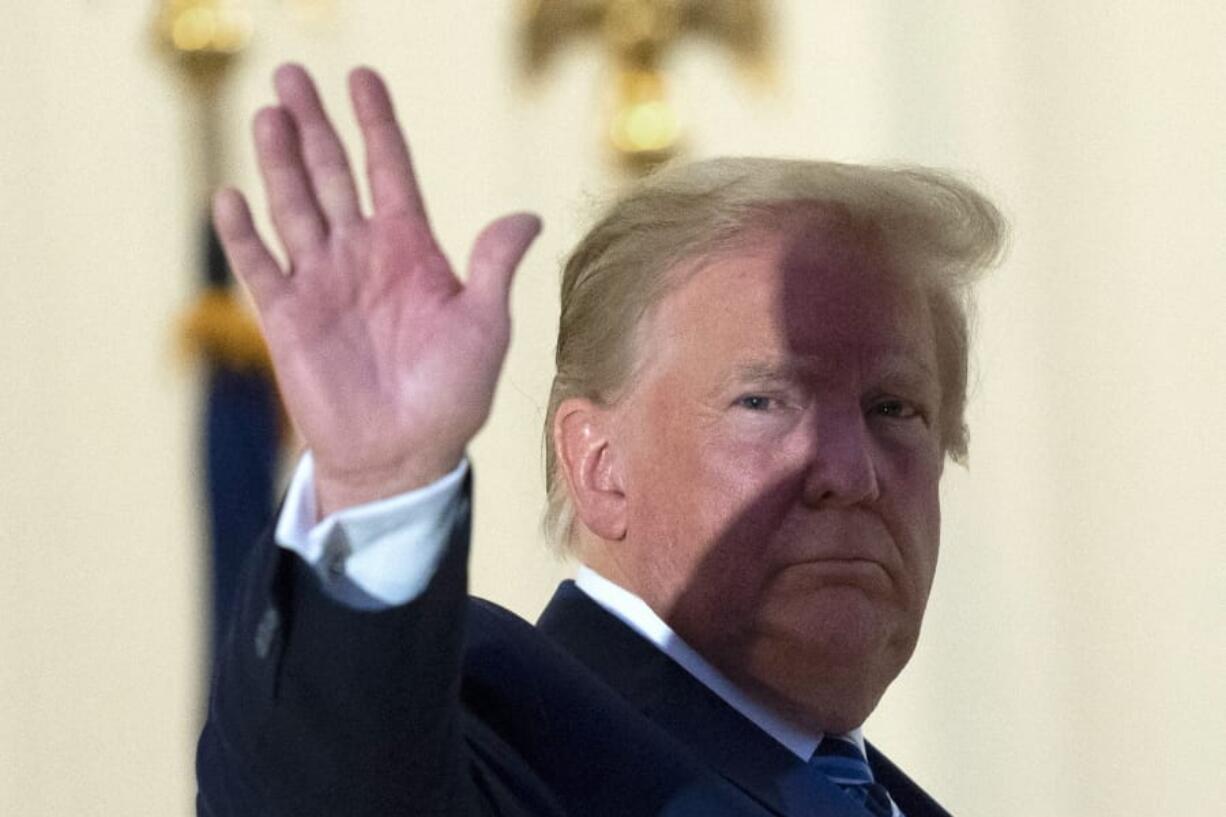 President Donald Trump waves from the Blue Room Balcony upon returning to the White House Monday, Oct. 5, 2020, in Washington, after leaving Walter Reed National Military Medical Center, in Bethesda, Md. Trump announced he tested positive for COVID-19 on Oct. 2.