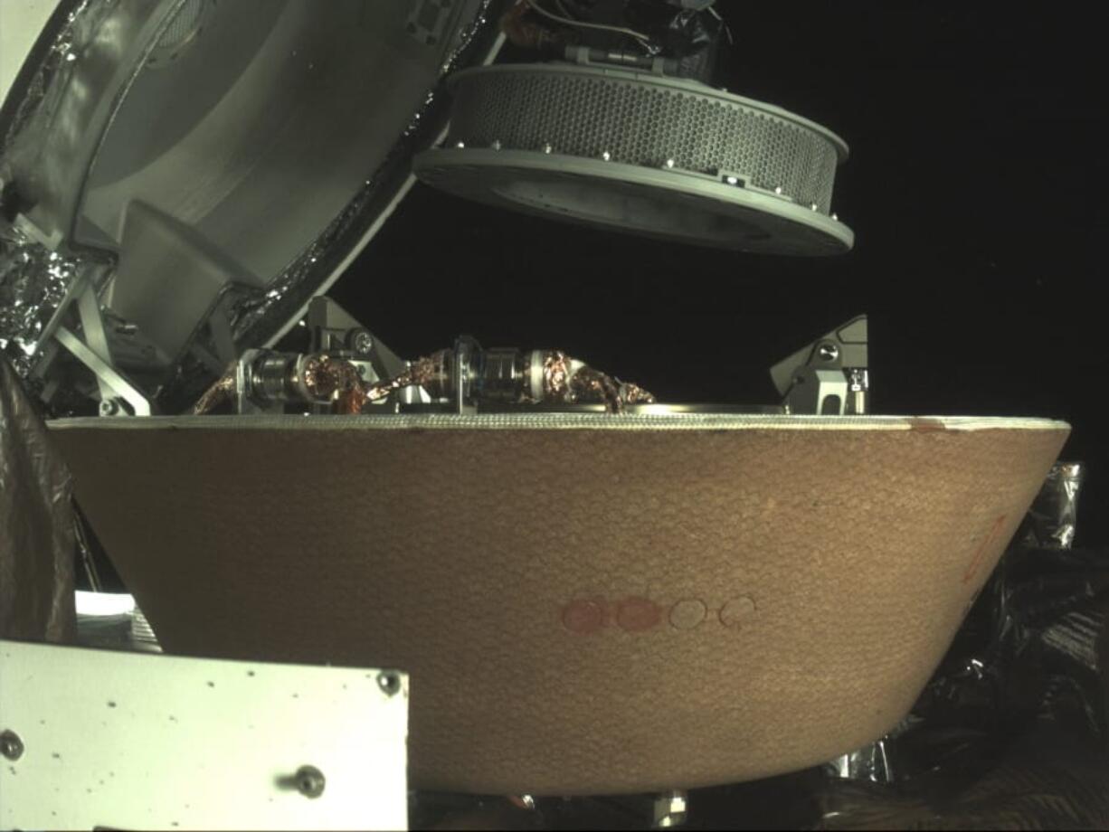 In this undated image provided by NASA, a sample container hovers over a capsule on the Osiris-Rex spacecraft near the asteroid Bennu. The capsule will eventually return to Earth with rubble collected in the container on Oct. 20, 2020, from the asteroid&#039;s surface.