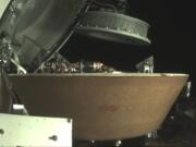 In this undated image provided by NASA, a sample container hovers over a capsule on the Osiris-Rex spacecraft near the asteroid Bennu. The capsule will eventually return to Earth with rubble collected in the container on Oct. 20, 2020, from the asteroid&#039;s surface.