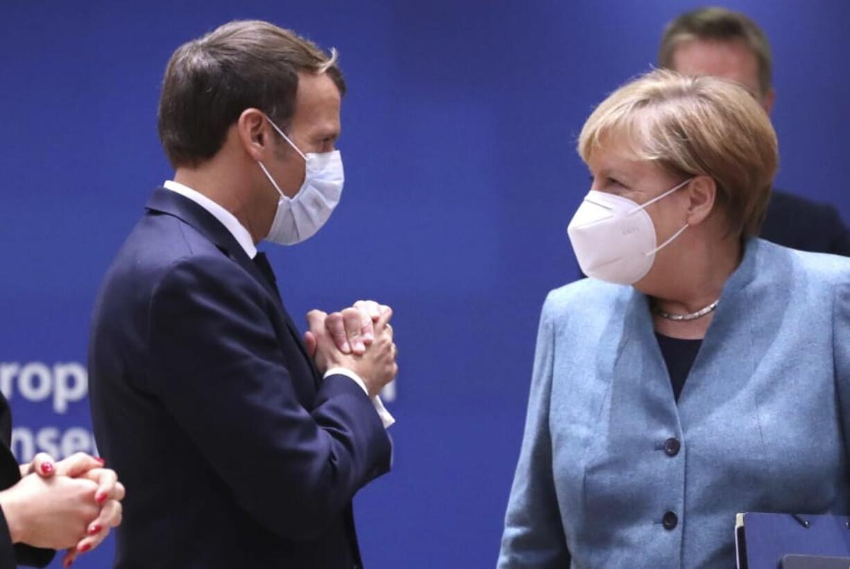 German Chancellor Angela Merkel, right, speaks with French President Emmanuel Macron arrives for a round table meeting at an EU summit at the European Council building in Brussels, Thursday, Oct. 15, 2020. European Union leaders are meeting in person for a two-day summit amid the worsening coronavirus pandemic to discuss topics ranging from Brexit to climate and relations with Africa.