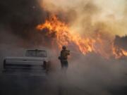 Firefighter Raymond Vasquez battles the Silverado Fire Monday, Oct. 26, 2020, in Irvine, Calif. A fast-moving wildfire forced evacuation orders for 60,000 people in Southern California on Monday as powerful winds across the state prompted power to be cut to hundreds of thousands to prevent utility equipment from sparking new blazes. (AP Photo/Jae C.