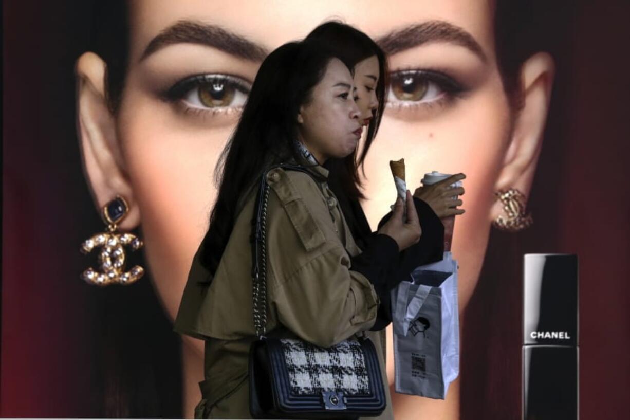 Women eating snack walk by a Chanel cosmetic shop at the capital city&#039;s popular shopping mall in Beijing, Monday, Oct. 19, 2020.