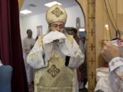 In this Sunday, Aug. 18, 2013 photo, Father Reweis Khalil brings the bread (Body of Christ) to worshippers during Sunday service at St. George Coptic Orthodox Church in Hampton, VA., on Sunday, Aug. 18, 2013. Khalil was removed from the priesthood in July. Sally Zakhari has alleged, including in a police report and to Coptic Church officials, that Khalil has sexually abused her. Khalil has denied the allegations through his attorney. (The&#039; N.