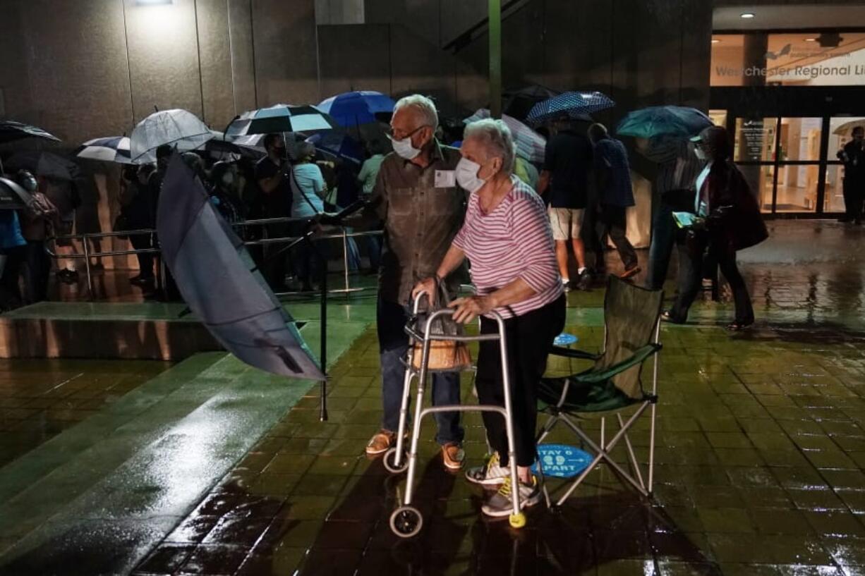 A couple stands in line as rain falls on voters waiting for the precinct to open, Monday, Oct. 19, 2020 in Miami. Florida begins in-person early voting in much of the state Monday. With its 29 electoral votes, Florida is crucial to both candidates in order to win the White House.