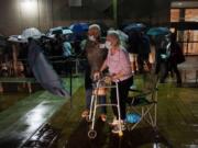 A couple stands in line as rain falls on voters waiting for the precinct to open, Monday, Oct. 19, 2020 in Miami. Florida begins in-person early voting in much of the state Monday. With its 29 electoral votes, Florida is crucial to both candidates in order to win the White House.