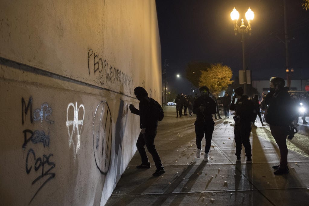 Protesters tag a wall with spray paint in downtown Vancouver Friday night. Some windows also were smashed.