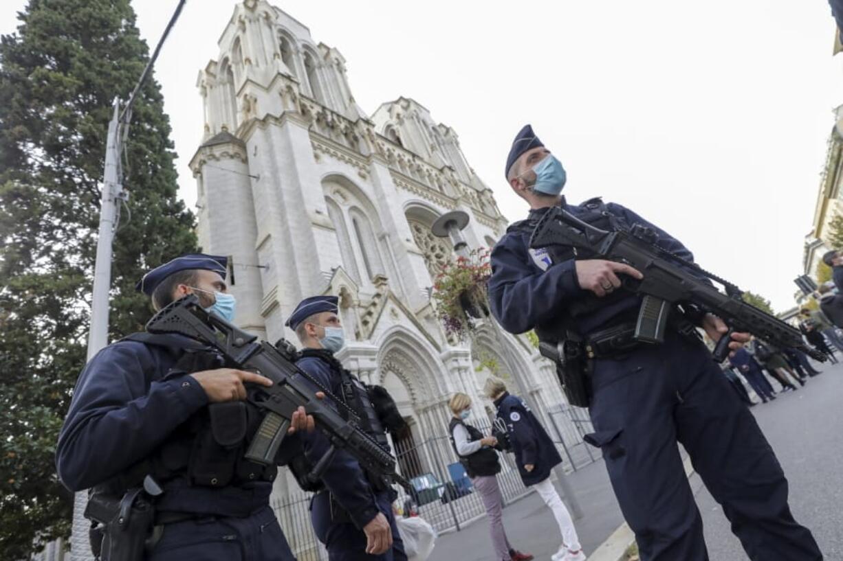 French police officers stand near Notre Dame church in Nice, southern France, Thursday, Oct. 29, 2020. French President Emmanuel Macron has announced that he will more than double number of soldiers deployed to protect against attacks to 7,000 after three people were killed at a church Thursday.