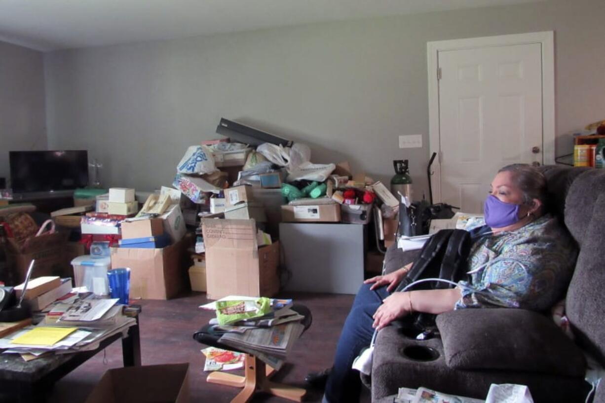 In this photo taken Thursday, Oct. 8, 2020, Houston resident Alice Torres sits inside her home, which had been damaged during Hurricane Harvey in 2017. Torres says she has not unpacked boxes of belongings in her living room because she is still waiting for help from a city program to finish repairs in her home. This week, the state of Texas took over the program over what it says is slow progress the program has made in repairing homes. Torres and other residents who have applied for assistance say they&#039;re worried the takeover could lead to more delays. (AP Photo/Juan A.