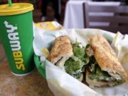 FILE - In this Friday, Feb. 23, 2018 file photo, the Subway logo is seen on a soft drink cup next to a sandwich at a restaurant in Londonderry, N.H.. Ireland&#039;s Supreme Court has ruled that bread sold by the fast food chain Subway contains so much sugar that it cannot be legally defined as bread.