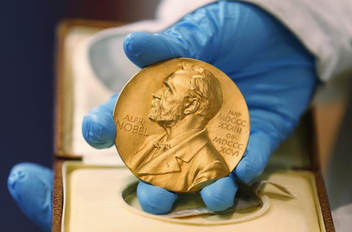 FILE - In this April 17, 2015, file photo, a national library employee shows a gold Nobel Prize medal in Bogota, Colombia. The Nobels, with new winners announced starting Monday, Oct. 5, 2020, often concentrate on unheralded, methodical, basic science.