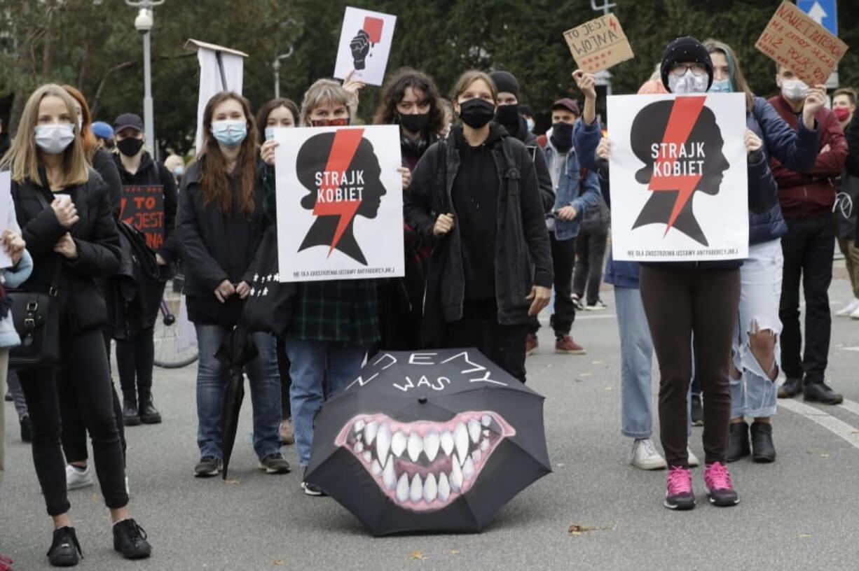 Women&#039;s rights activists with posters of the Women&#039;s Strike action protest against recent tightening of Poland&#039;s restrictive abortion law in front of the parliament building as inside, guards had to be used to shield right-wing ruling party leader Jaroslaw Kaczynski from angry opposition lawmakers, in Warsaw, Poland, on Tuesday, Oct. 27, 2020. Massive nationwide protests have been held ever since a top court ruled Thursday that abortions due to fetal congenital defects are unconstitutional. Slogan reads &#039;Women&#039;s Strike&#039;.