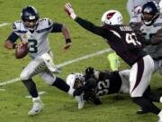 Seattle Seahawks quarterback Russell Wilson (3) escapes the reach of Arizona Cardinals strong safety Budda Baker (32) as outside linebacker Haason Reddick (43) pursues during the second half of an NFL football game, Sunday, Oct. 25, 2020, in Glendale, Ariz. (AP Photo/Ross D.